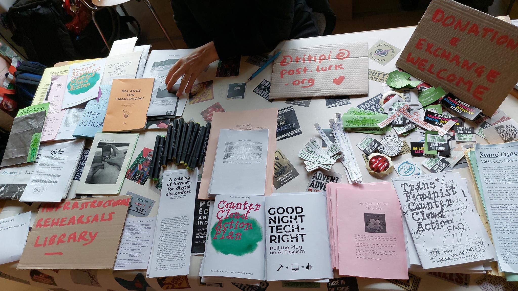 Amsterdam, March 2025. A table seen from above is filled with stickers, zines and other publications
